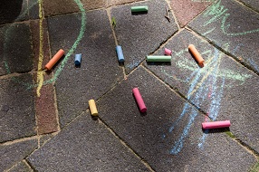 Sticks of coloured chalk and drawing on a brick path
