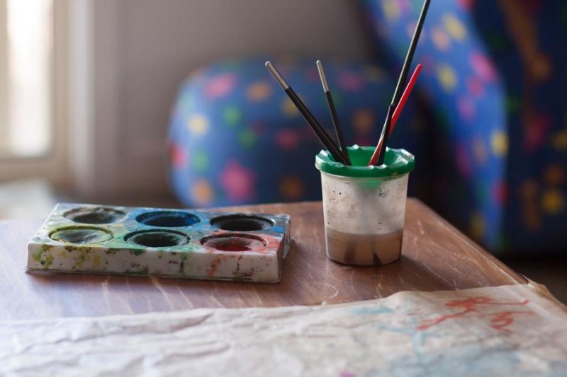 Paint brushes in a pot and palate on a table
