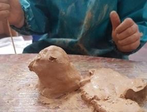 Child sculpting an eagle head with clay.