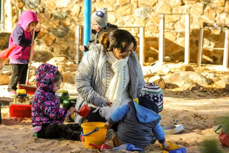 Educator with children outside winter sandpit