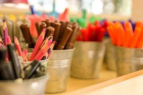 Colourful pencils in tins on table