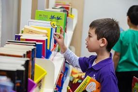 Boy selecting book from book shelf