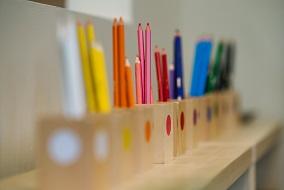Colourful pencils lined up on bookshelf