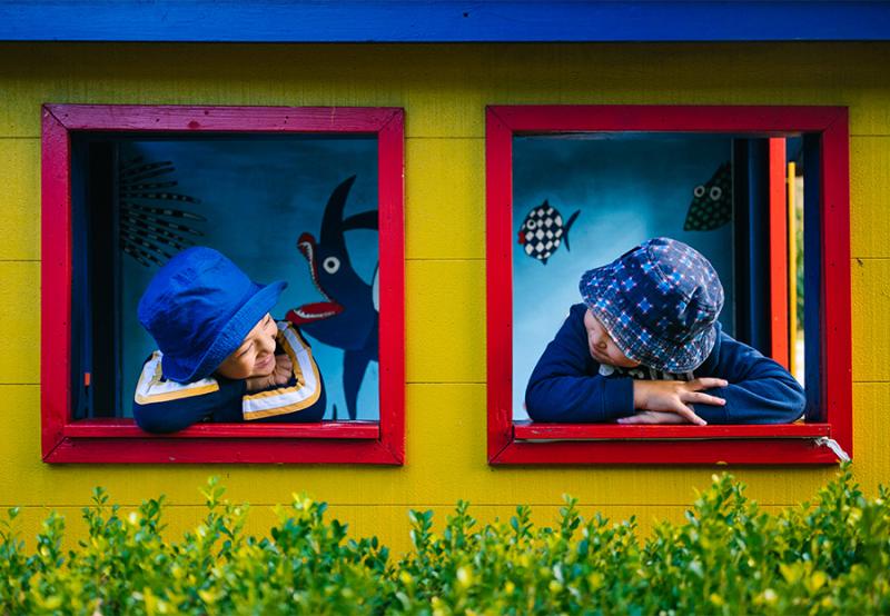 Two children looking at each other through windows of playhouse