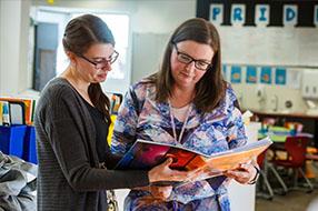 Two educators looking at a book together