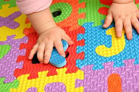 Child's hand on alphabet floor mat