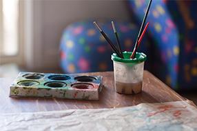 Paints and water tub with paintbrushes
