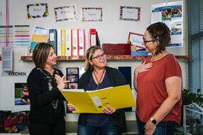 Three educators talking in staff room