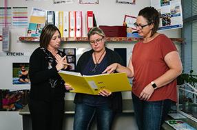Three educators looking at a folder together