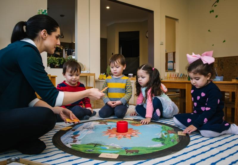 Educator and four children sitting on floor with pond playrug