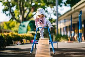 Child wearing hat and climbing on frame