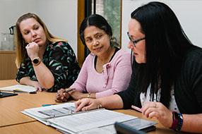 Three female educators looking at a file together