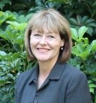 Headshot of ACECQA CEO Gabrielle Sinclair against leafy background
